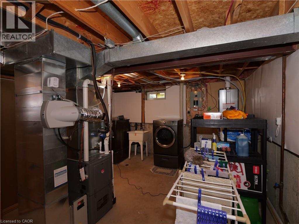 Utility area featuring exposed joist ceiling, concrete flooring, washer and dryer, and a utility sink - 771 Monsarrat Avenue, London, ON