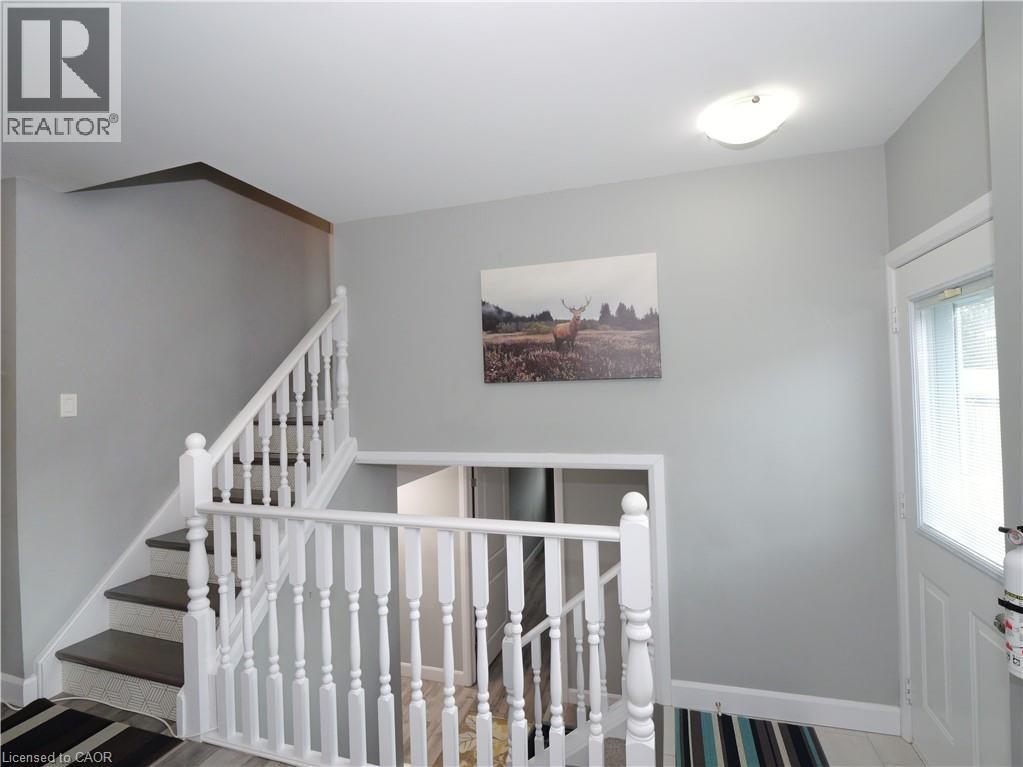 Staircase featuring dark wood-finish treads, white balusters, and light gray wall paint - 771 Monsarrat Avenue, London, ON