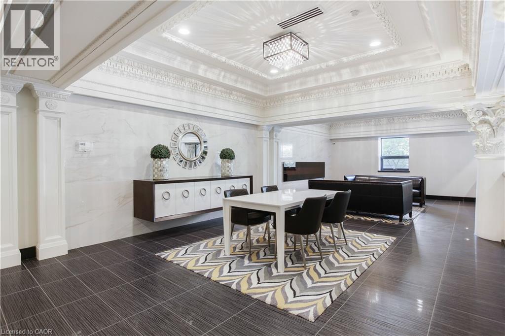 Spacious common area featuring decorative crown molding, recessed lighting, a modern chandelier, dark tile flooring, and a window providing natural light - 112 King Street E Unit# Ph6, Hamilton, ON - Indoor Photo Showing Dining Room