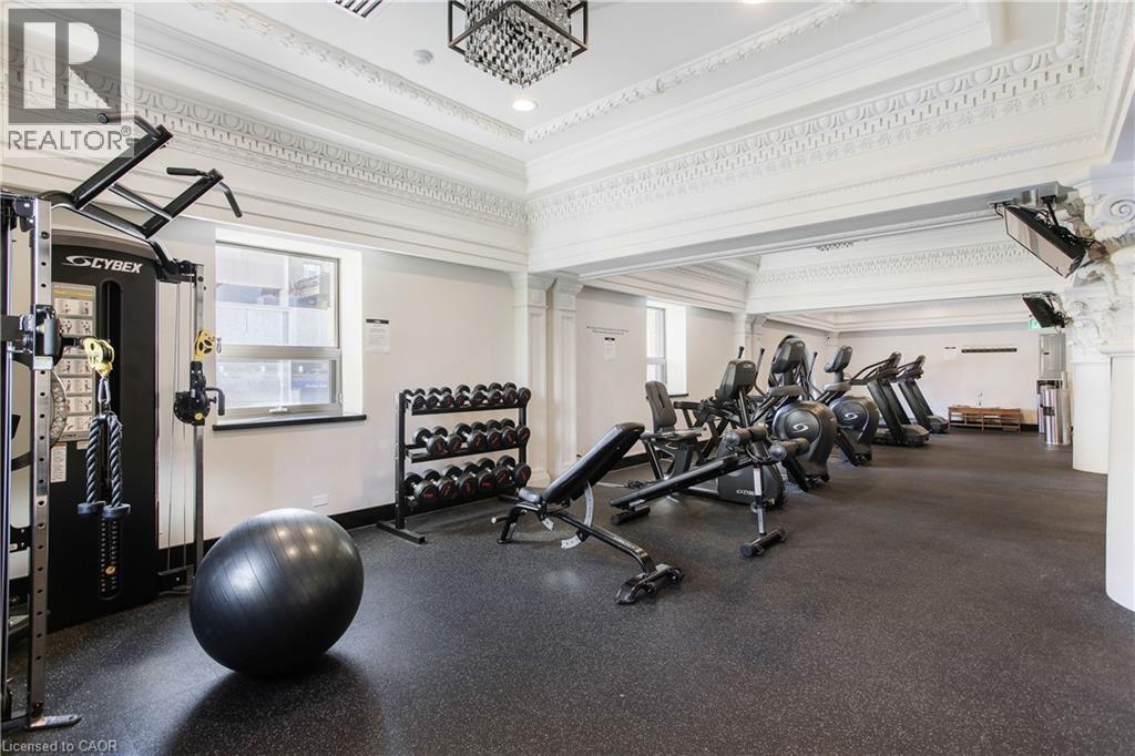 Fitness center featuring durable rubber flooring, extensive cardio equipment, a comprehensive weight machine, and dumbbell rack - 112 King Street E Unit# Ph6, Hamilton, ON - Indoor Photo Showing Gym Room