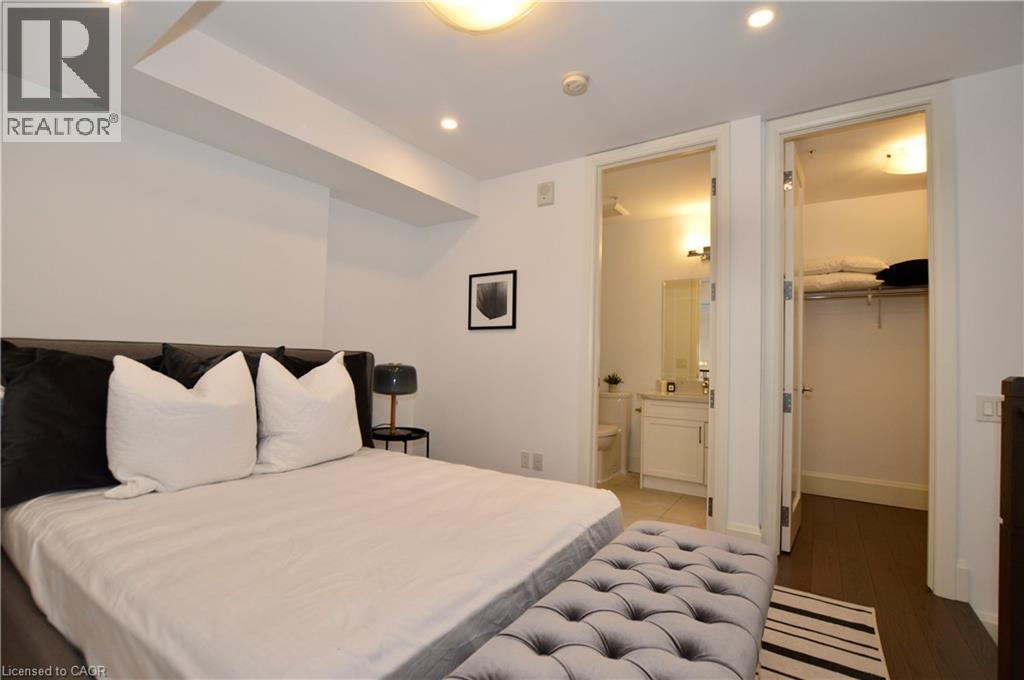 Bedroom featuring recessed lighting, a built-in architectural soffit, a hardwood-finish flooring, a full-lite interior door opening to a bathroom, and another full-lite interior door opening to a clos - 112 King Street E Unit# Ph6, Hamilton, ON - Indoor Photo Showing Bedroom