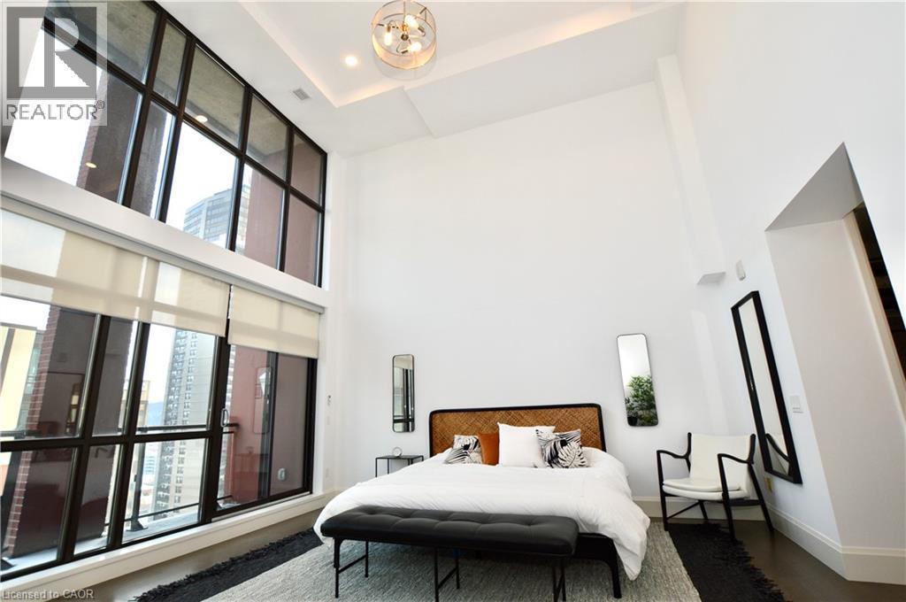 Soaring ceilings and expansive multi-story windows define this bedroom space - 112 King Street E Unit# Ph6, Hamilton, ON - Indoor Photo Showing Bedroom