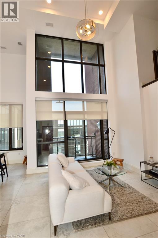 Two-story windows with integrated roller shades, high ceilings, recessed lighting, a modern spherical chandelier, and light-toned tile flooring - 112 King Street E Unit# Ph6, Hamilton, ON - Indoor