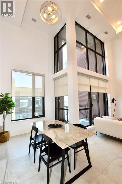Dramatic two-story living area featuring a full wall of floor-to-ceiling windows with roller shades, recessed lighting, and a contemporary chandelier - 112 King Street E Unit# Ph6, Hamilton, ON - Indoor Photo Showing Other Room