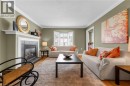 Spacious room featuring a fireplace with a slate surround and mantle, hardwood flooring, bay window with plantation shutters, and crown molding - 50 Spadara Drive, Hamilton, ON  - Indoor Photo Showing Living Room With Fireplace 