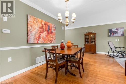 Dining area featuring wood-finish flooring, a traditional chandelier, crown molding, chair rail molding, and a built-in china cabinet - 50 Spadara Drive, Hamilton, ON - Indoor Photo Showing Dining Room