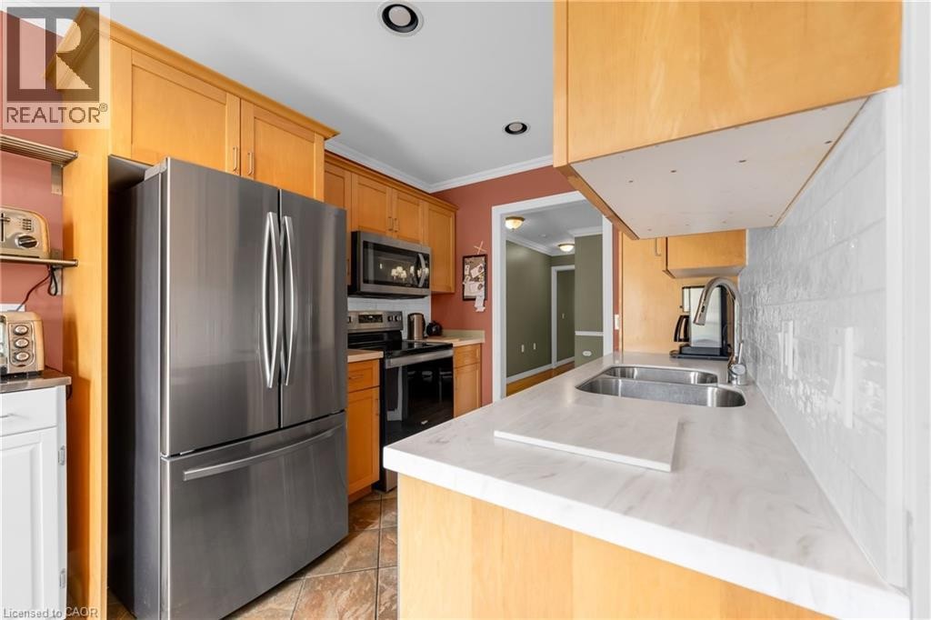 Kitchen featuring light wood cabinetry, stainless steel appliances, a double basin sink, white subway tile backsplash, and light-toned countertops - 50 Spadara Drive, Hamilton, ON - Indoor Photo Showing Kitchen With Double Sink