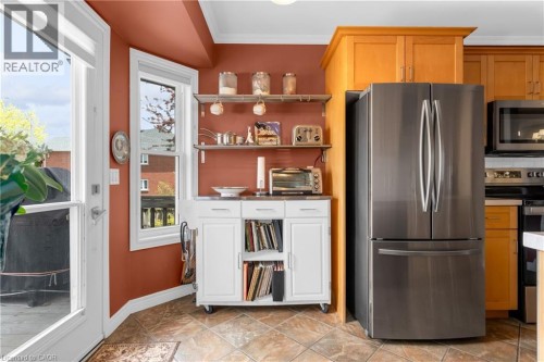 Stainless steel French door refrigerator, wood-finish cabinetry, tile flooring, and a white door with glass paneling - 50 Spadara Drive, Hamilton, ON - Indoor Photo Showing Kitchen