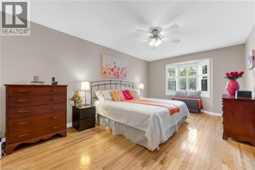 Bedroom featuring hardwood flooring, a ceiling fan, a bay window with plantation shutters, and neutral wall tones - 50 Spadara Drive, Hamilton, ON - Indoor Photo Showing Bedroom