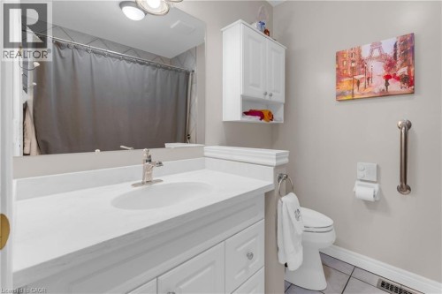 Bathroom featuring a white vanity with an integrated sink, brushed nickel faucet, wall-mounted mirror, white wall cabinetry, and tile flooring - 50 Spadara Drive, Hamilton, ON - Indoor Photo Showing Bathroom