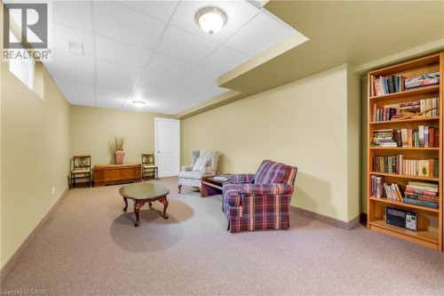 Carpeted room featuring a drop ceiling with recessed lighting and a full-height wooden built-in bookshelf - 50 Spadara Drive, Hamilton, ON - Indoor
