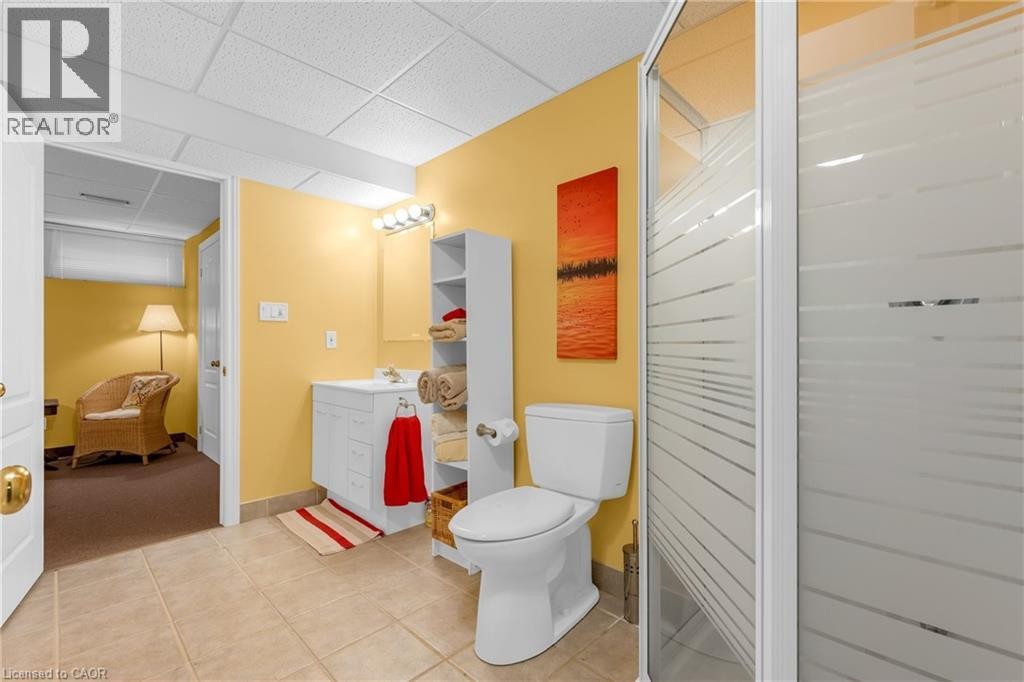 Bathroom featuring a white vanity with built-in storage, a toilet, and a stand-up shower with frosted glass enclosure - 50 Spadara Drive, Hamilton, ON - Indoor Photo Showing Bathroom