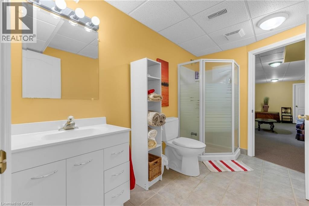 Full bathroom featuring a single vanity with storage, corner shower enclosure, toilet, and tile flooring - 50 Spadara Drive, Hamilton, ON - Indoor Photo Showing Bathroom