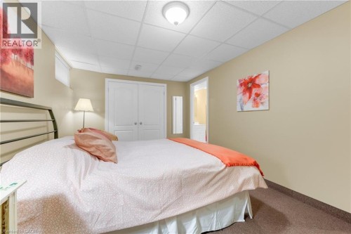 Carpeted room featuring neutral-toned walls, a drop ceiling, and a flush-mount ceiling light - 50 Spadara Drive, Hamilton, ON - Indoor Photo Showing Bedroom