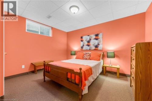 Carpeted room featuring a white drop ceiling, vibrant coral-painted walls, and a window with a white frame - 50 Spadara Drive, Hamilton, ON - Indoor Photo Showing Bedroom