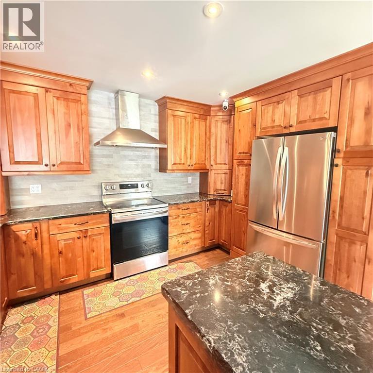 Well-appointed kitchen featuring wood-finish cabinetry, stainless steel appliances, and dark speckled countertops - 82 Blackwood Crescent, Hamilton, ON