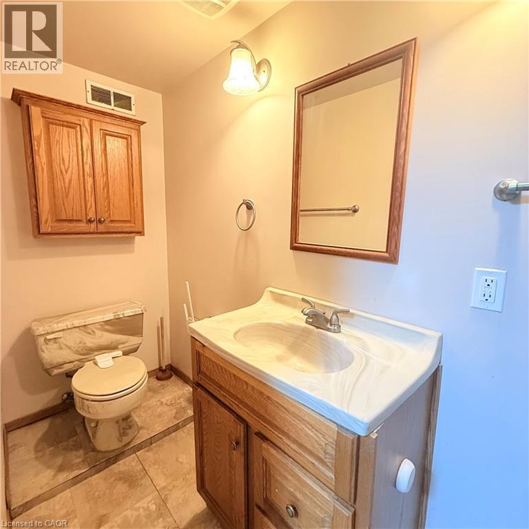 Bathroom featuring a wood vanity with integrated sink, a matching wood-framed mirror, and a wood wall cabinet - 82 Blackwood Crescent, Hamilton, ON