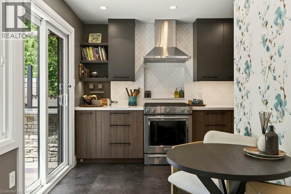 Contemporary kitchen featuring a stainless steel range with matching hood, white subway tile backsplash, and dark wood-finish cabinetry - 99 Hillcrest Avenue, Hamilton, ON - Indoor