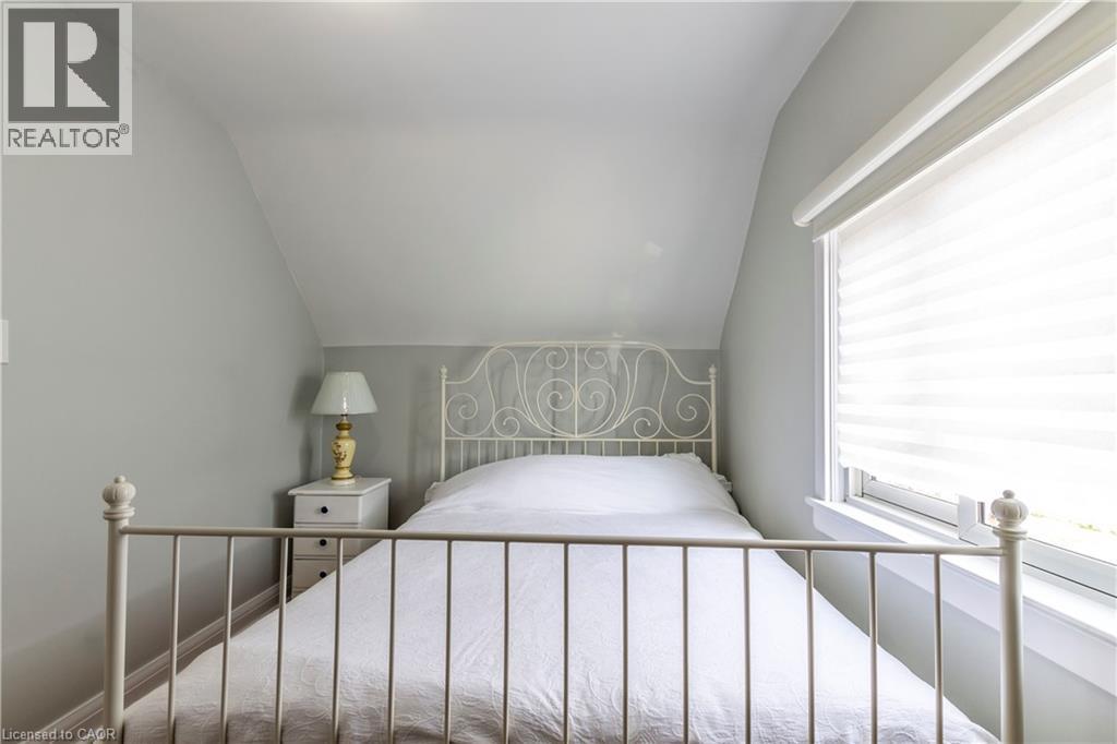 Attic room with sloped ceiling, light gray walls, and a window with white blinds - 20 West 1St Street, Hamilton, ON