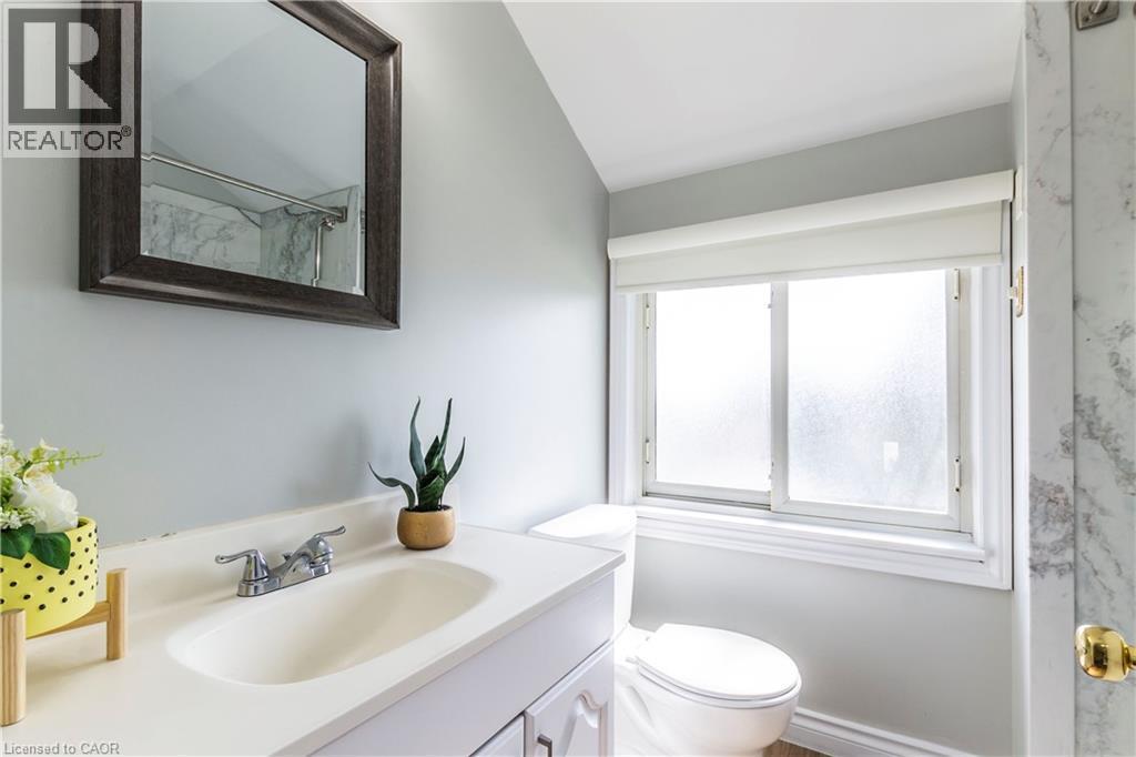 Bathroom featuring a white vanity with an integrated sink, chrome faucet, and framed mirror - 20 West 1St Street, Hamilton, ON