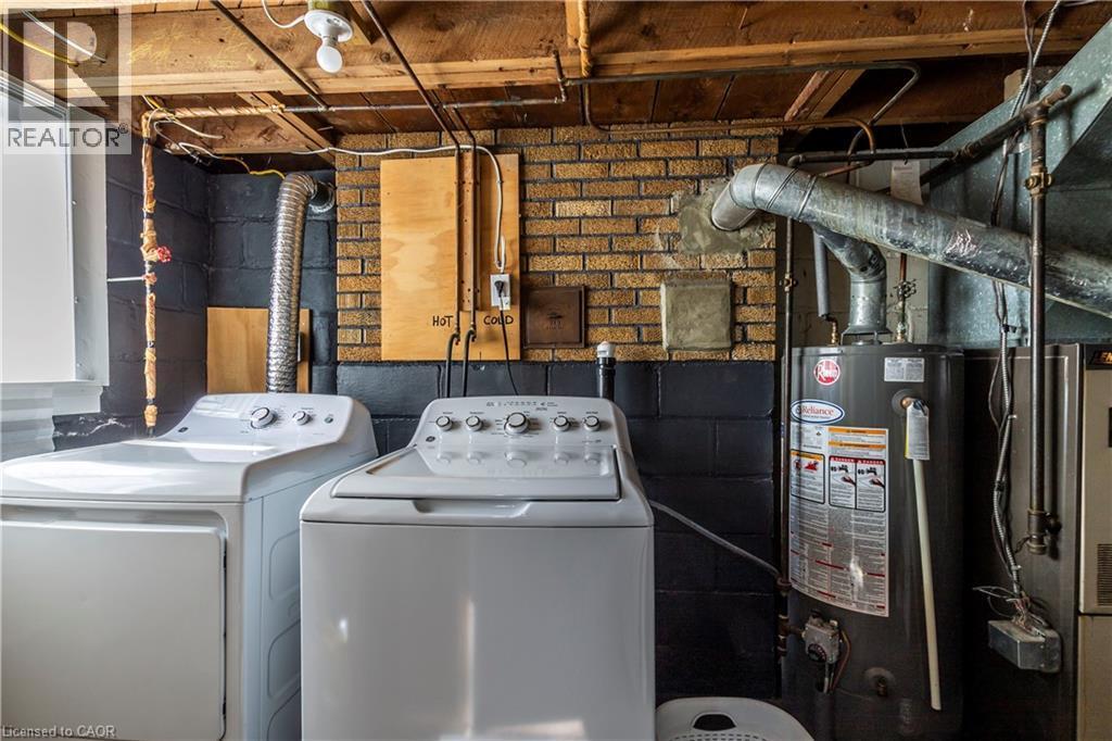 Laundry area featuring a top-load washing machine, a front-load dryer, and a water heater - 20 West 1St Street, Hamilton, ON