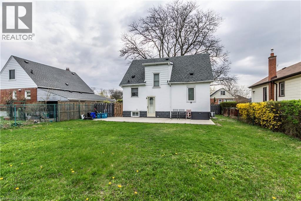 Expansive green lawn with a concrete patio extending from the rear of the home - 20 West 1St Street, Hamilton, ON