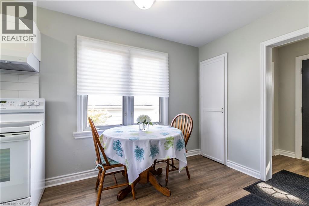 Kitchen featuring wood-finish flooring, white cabinetry, and a white tile backsplash - 20 West 1St Street, Hamilton, ON