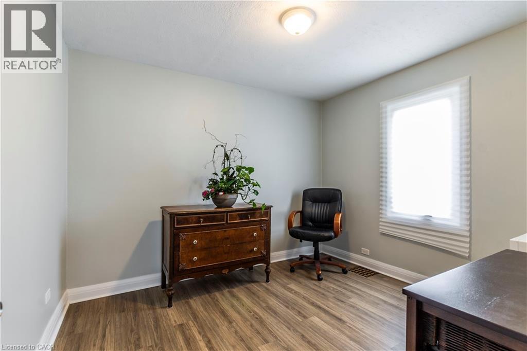 Room featuring wood-finish flooring, light gray walls, a single window with blinds, white baseboards, and a ceiling-mounted light fixture - 20 West 1St Street, Hamilton, ON