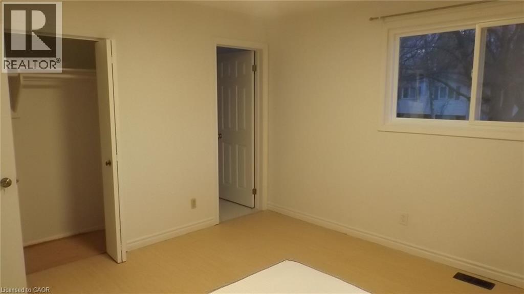 Well-lit room featuring neutral wall paint, light-colored flooring, a window offering exterior views, a built-in closet with shelving, and a paneled door - 68 Austin Drive, Waterloo, ON - Indoor Photo Showing Other Room