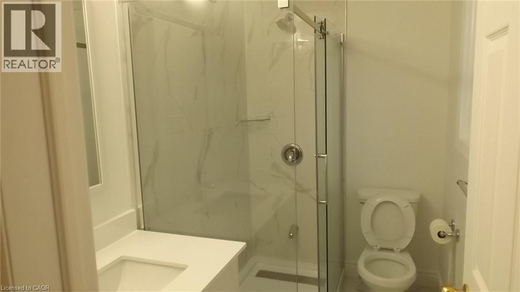 Bathroom featuring a glass-enclosed shower with a rainfall showerhead, white-veined tile surround, and a linear drain - 68 Austin Drive, Waterloo, ON - Indoor Photo Showing Bathroom