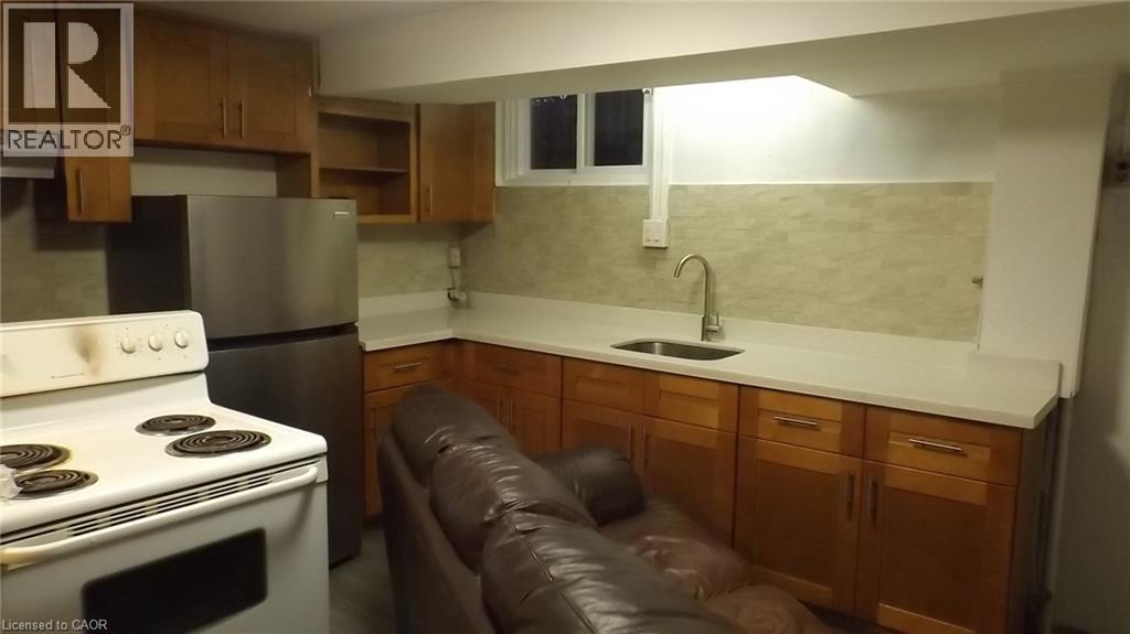 Kitchenette featuring wood-finish cabinetry, light-toned countertops, a stainless steel refrigerator, and a white electric range - 68 Austin Drive, Waterloo, ON - Indoor Photo Showing Kitchen