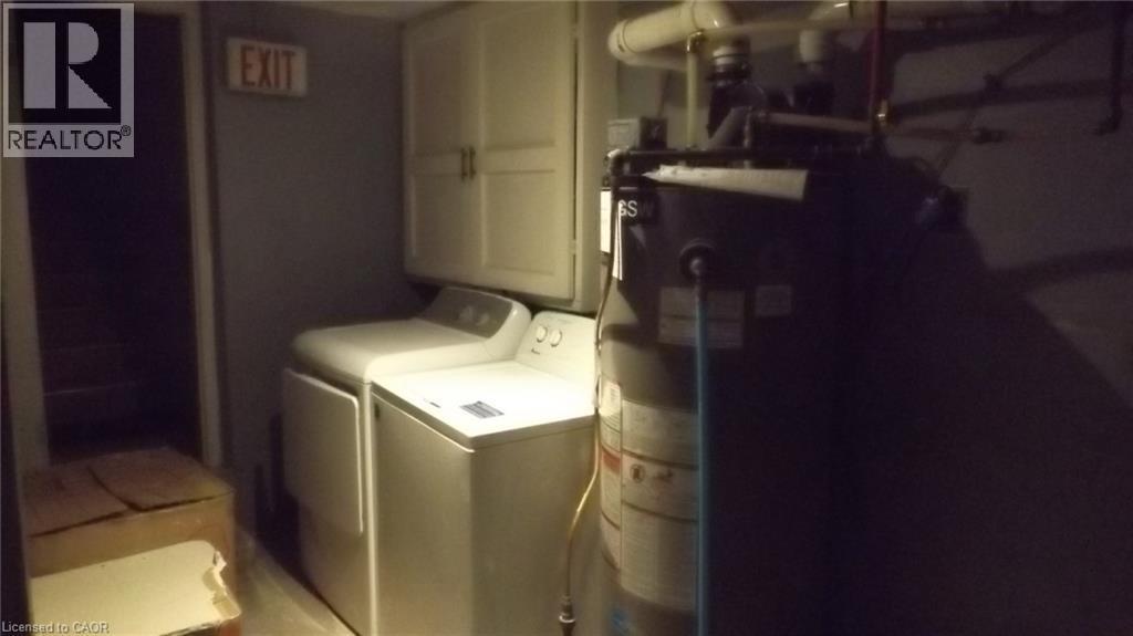 Utility area featuring a top-load washer, a front-load dryer, and upper cabinetry - 68 Austin Drive, Waterloo, ON - Indoor Photo Showing Laundry Room