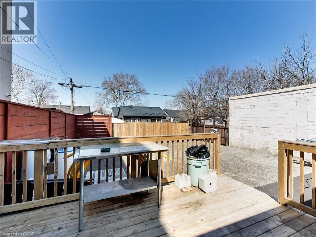 Outdoor wooden deck with railings, providing access to a gravel-surfaced yard - 229 Parkdale Avenue N, Hamilton, ON