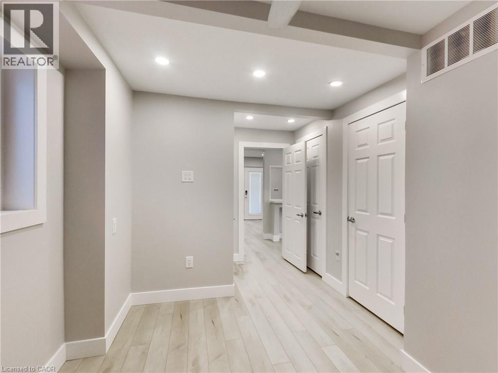 Hallway featuring light wood-finish flooring, recessed lighting, white baseboards, and multiple paneled doors - 229 Parkdale Avenue N, Hamilton, ON