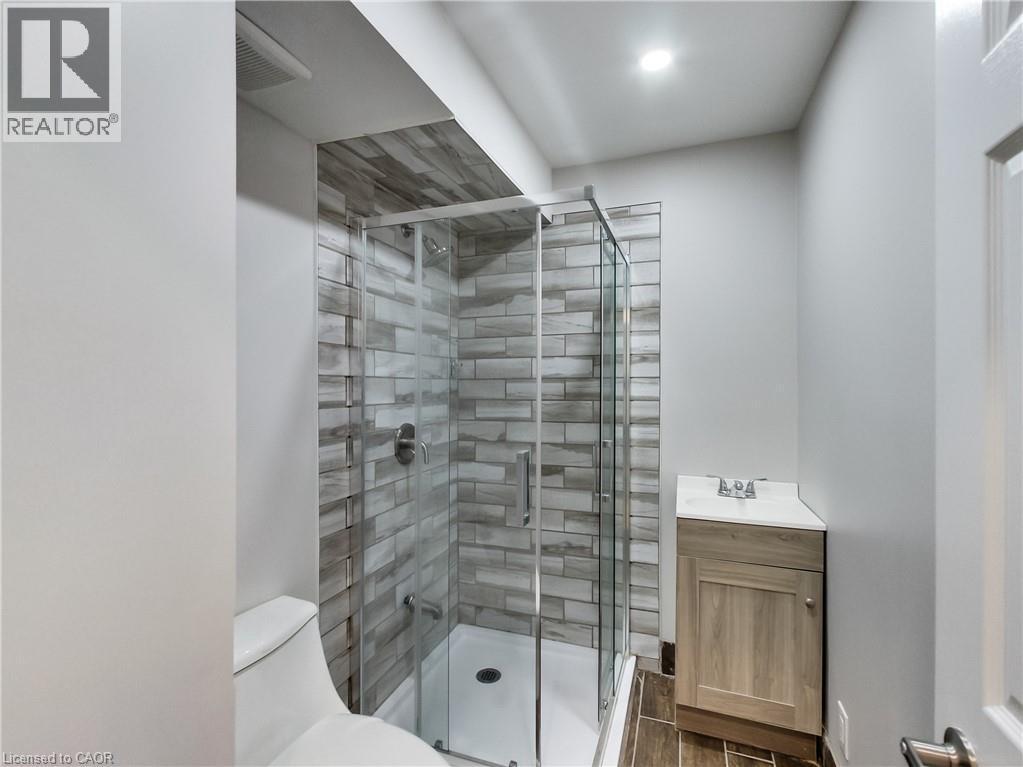 Contemporary bathroom with a glass-enclosed shower, featuring a tiled surround and a rain showerhead - 229 Parkdale Avenue N, Hamilton, ON