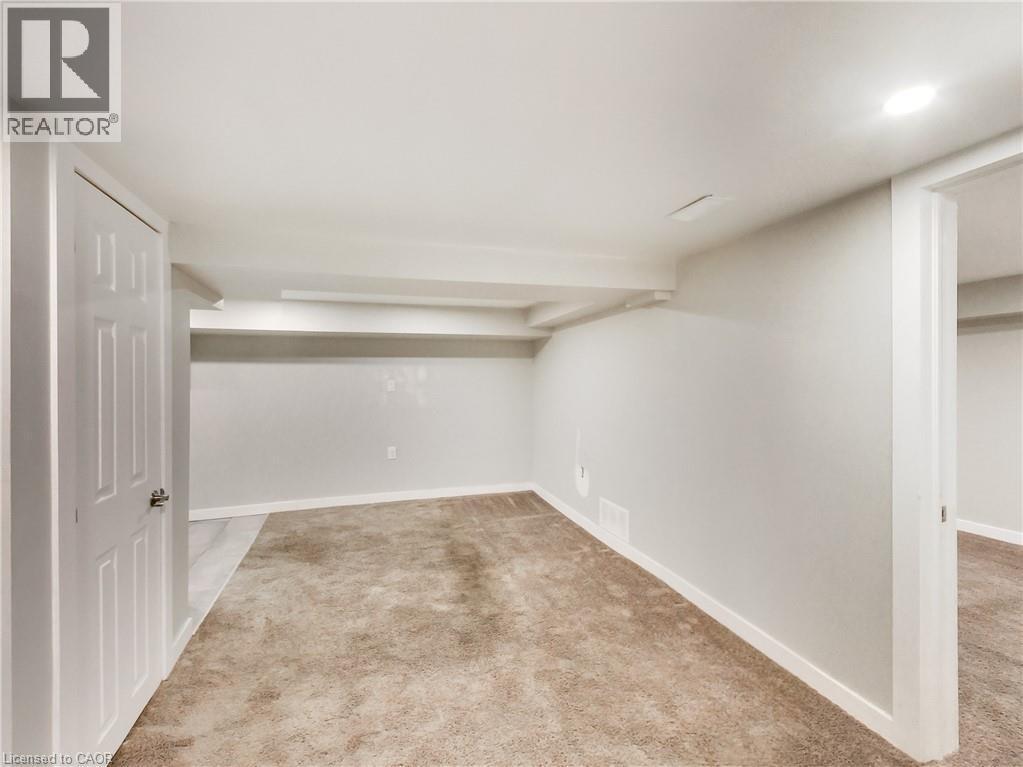 Spacious interior room featuring light-colored walls, recessed ceiling lighting, and neutral-toned carpeting - 229 Parkdale Avenue N, Hamilton, ON