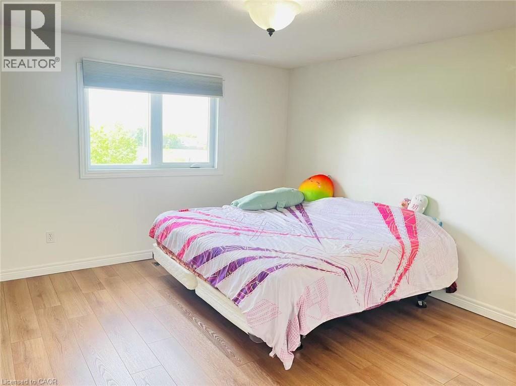 Light-filled room featuring wood-finish flooring, white baseboards, and a single window with a roller shade - 136 Hidden Creek Drive, Kitchener, ON