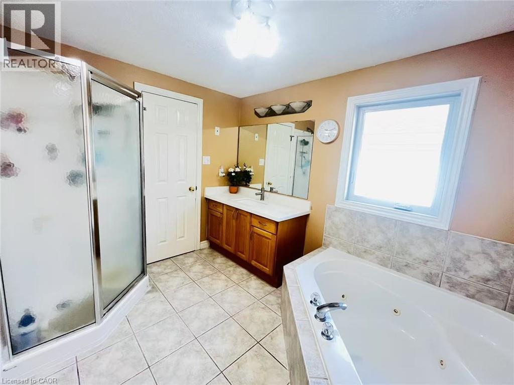 Bathroom featuring a jetted soaking tub, a stand-up shower with a glass enclosure, and a vanity with an integrated sink - 136 Hidden Creek Drive, Kitchener, ON