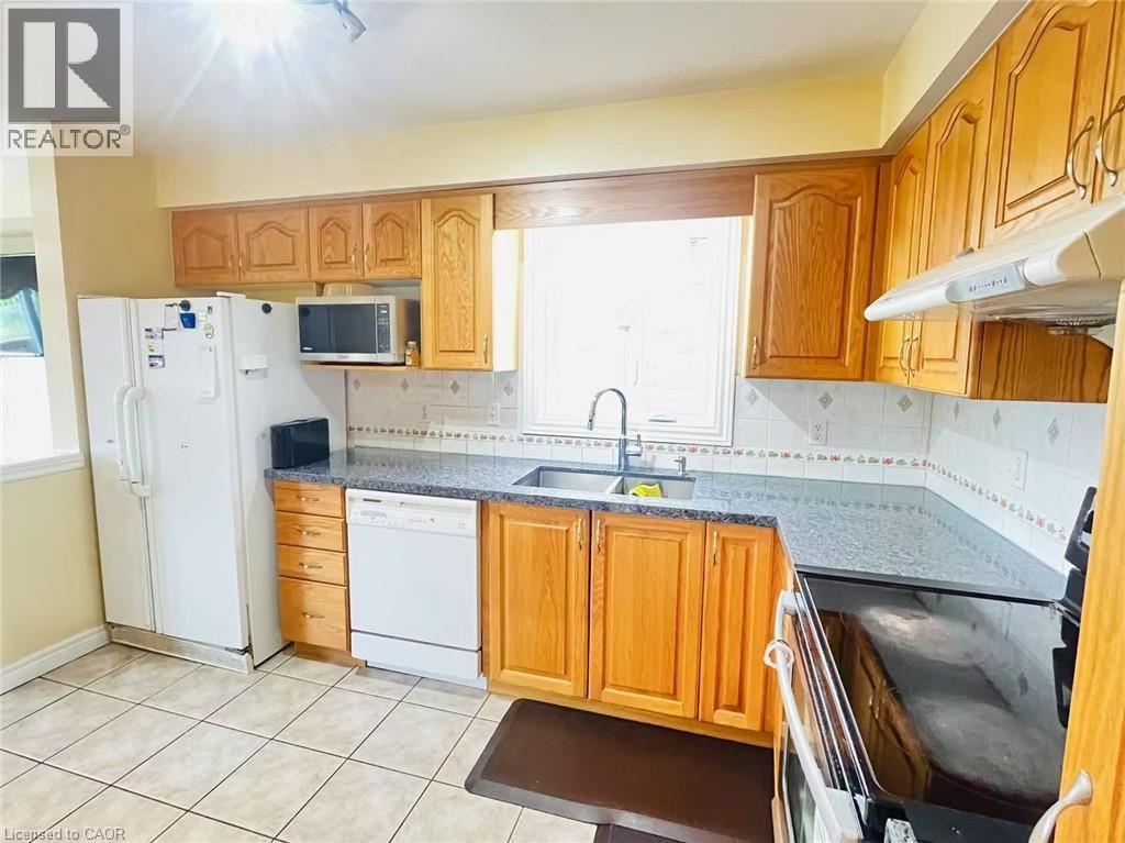 Kitchen featuring wood cabinetry, light-toned tile flooring, and a window above the sink - 136 Hidden Creek Drive, Kitchener, ON