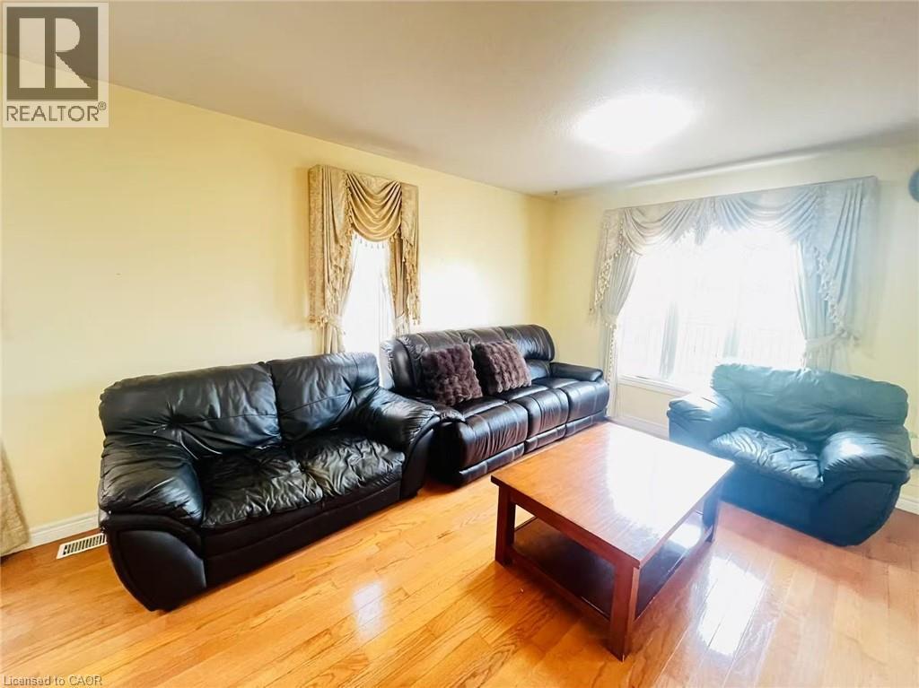 Living area featuring wood-finish flooring, light-toned wall paint, and a large window with draped treatments - 136 Hidden Creek Drive, Kitchener, ON