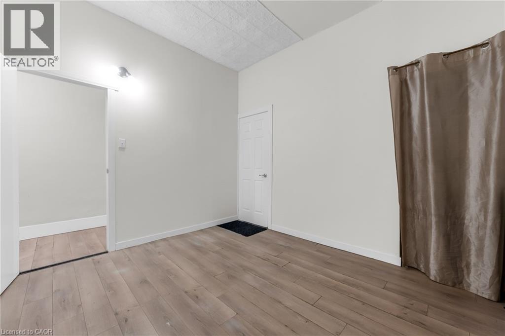 Room featuring wood-finish flooring, light neutral wall paint, and white baseboards - 1371 Main Street E, Hamilton, ON - Indoor Photo Showing Other Room