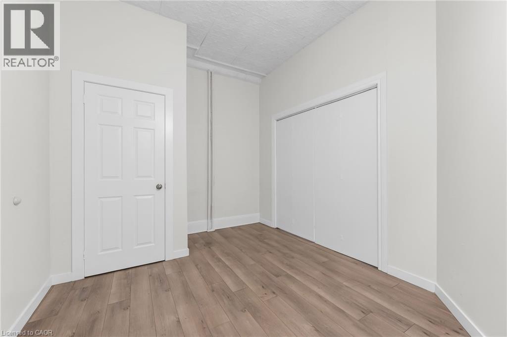 Neutral wall tones paired with wood-finish flooring - 1371 Main Street E, Hamilton, ON - Indoor Photo Showing Other Room