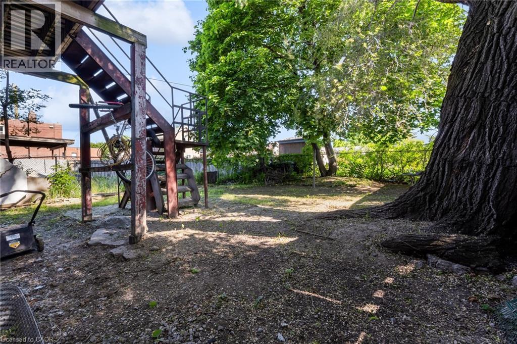 Spacious outdoor area featuring mature trees and a multi-level deck structure with stairs and metal railings - 1371 Main Street E, Hamilton, ON - Outdoor