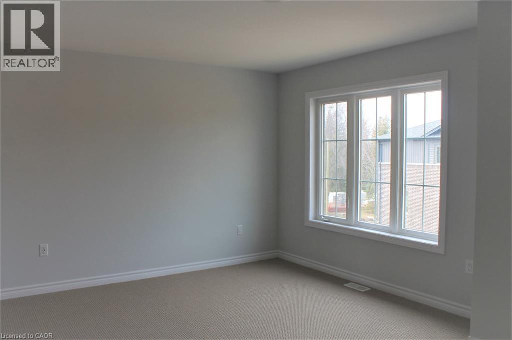 Light gray painted walls and neutral carpeting define this space, featuring a three-pane window with white trim - 124 Compass Trail Unit# 14, Cambridge, ON