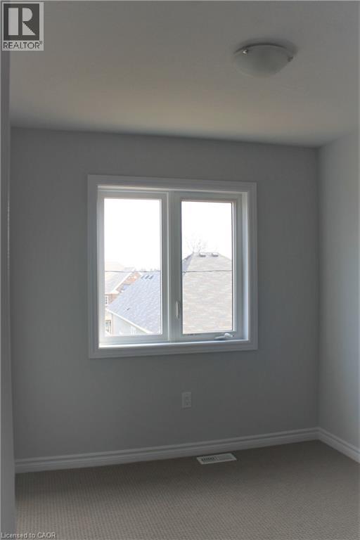 Carpeted room with a double-pane window and a flush-mount ceiling light - 124 Compass Trail Unit# 14, Cambridge, ON