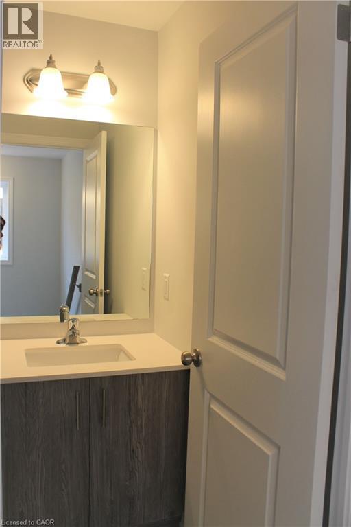 Contemporary bathroom vanity featuring a light-colored countertop with an integrated sink, brushed nickel faucet, and a wall-mounted mirror - 124 Compass Trail Unit# 14, Cambridge, ON