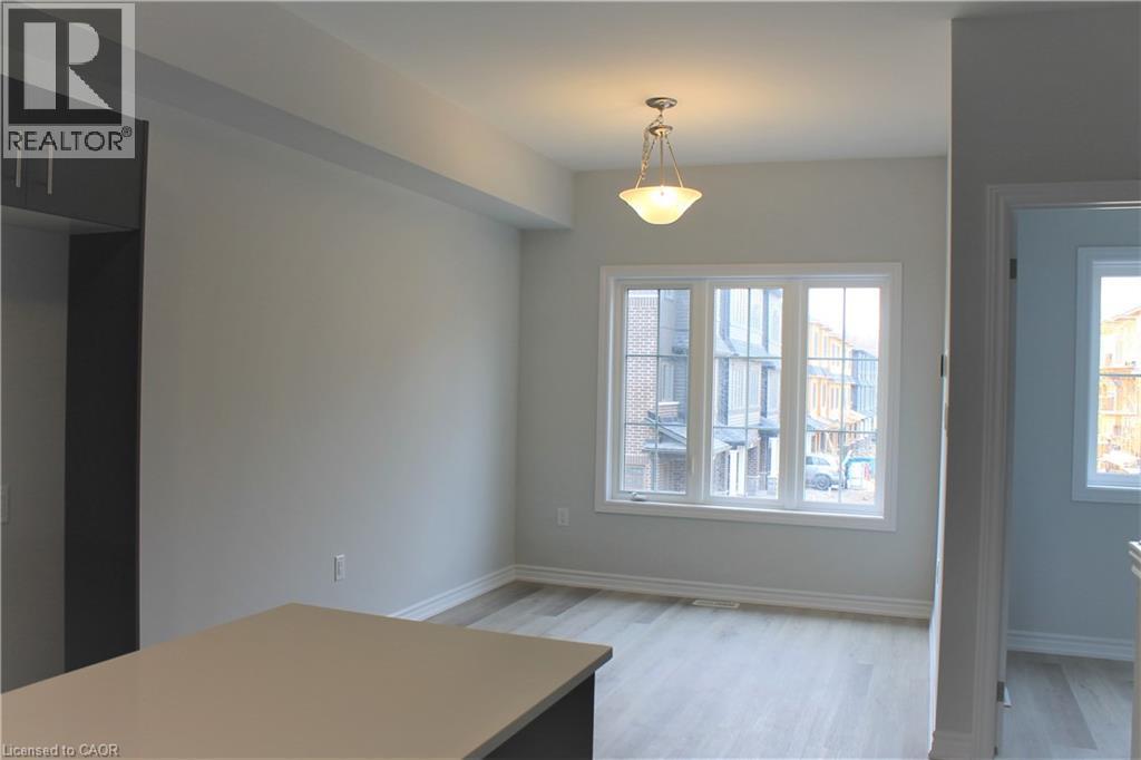 Bright interior space featuring a multi-pane window, wood-finish flooring, and a contemporary pendant light fixture - 124 Compass Trail Unit# 14, Cambridge, ON