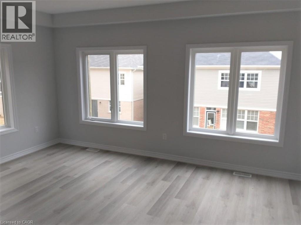 Spacious room featuring light gray walls, white trim, and wood-finish flooring - 124 Compass Trail Unit# 14, Cambridge, ON