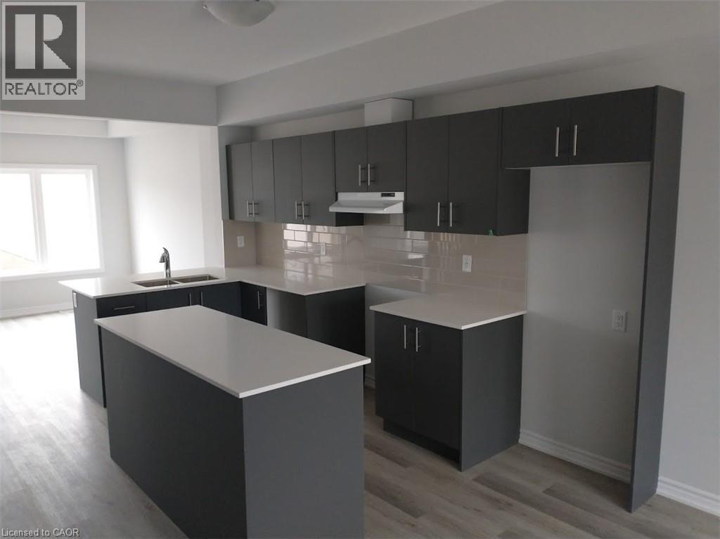 Contemporary kitchen featuring dark flat-panel cabinetry, light countertops, a central island, subway tile backsplash, and wood-finish flooring - 124 Compass Trail Unit# 14, Cambridge, ON