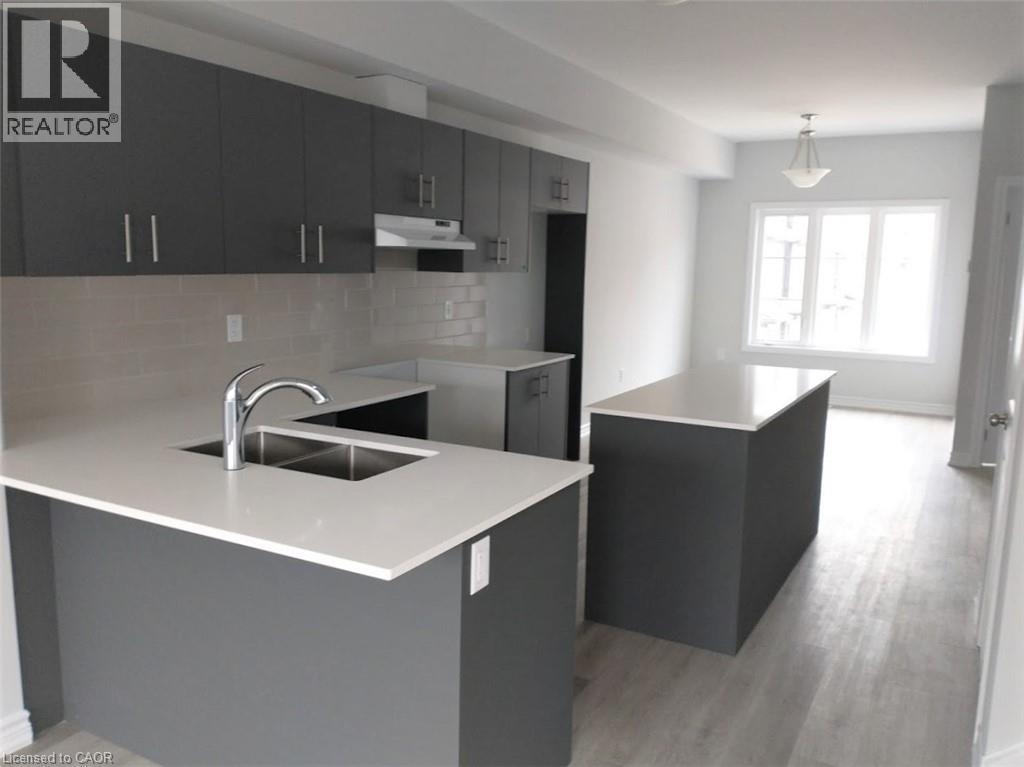 Modern kitchen featuring dark gray cabinetry, light-toned countertops, and a subway tile backsplash - 124 Compass Trail Unit# 14, Cambridge, ON